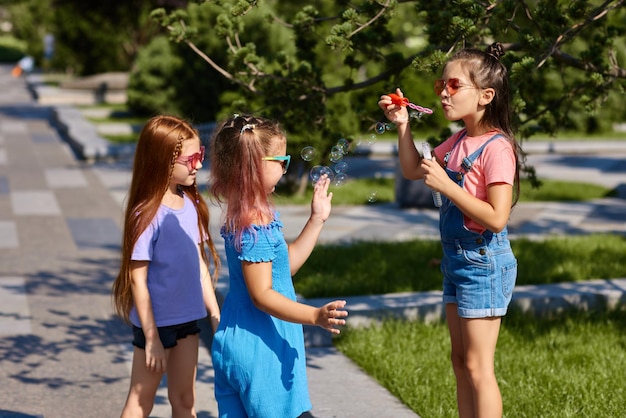 Niños jugando con pompas de jabón en el parque.