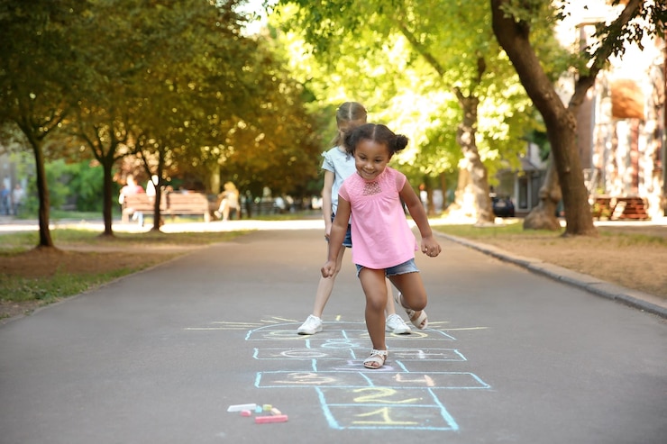 Foto niños jugando a la rayuela dibujada con tiza de colores sobre asfalto