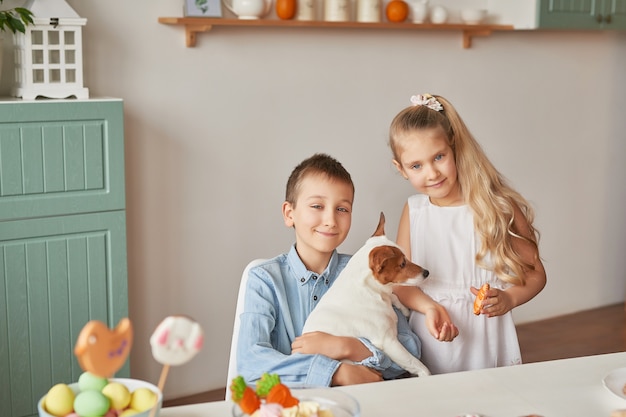 Niños jugando con su perro en una mesa decorada con Pascua