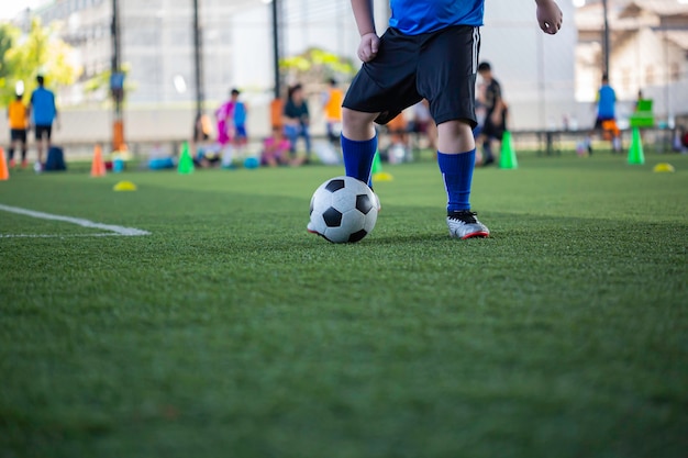 Niños jugando tácticas de control de balón de fútbol en el campo de hierba con antecedentes de formación Formación de niños en fútbol