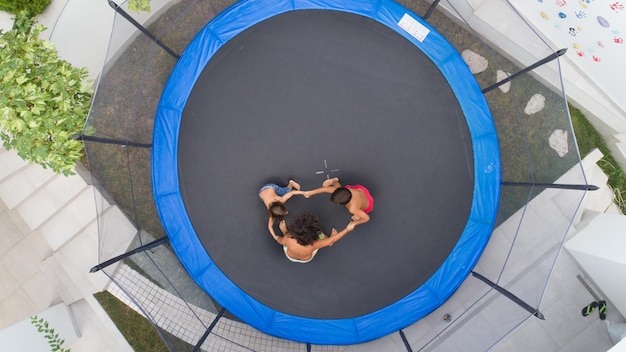 Niños jugando en trampolín vista aérea juntos