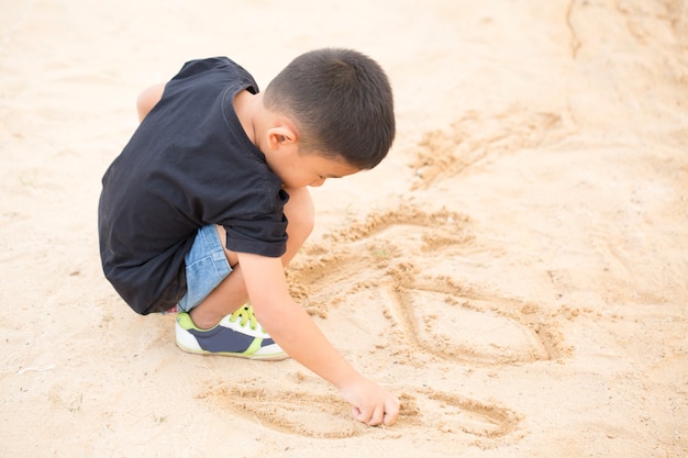 Niños de Kindergarten sentado arena en el campo de arena.