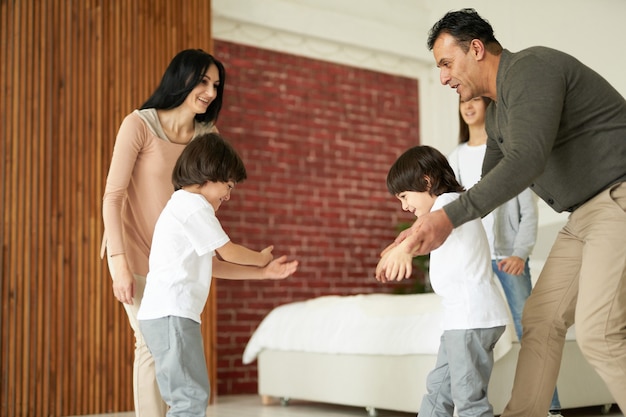 Niños latinos alegres niños gemelos sonriendo mientras se divierten con su hermana y sus padres