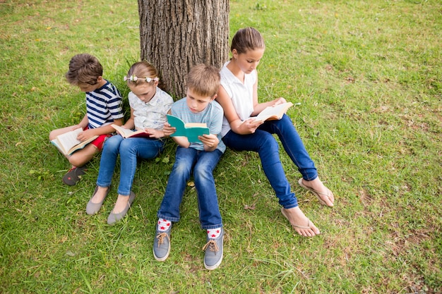 Niños leyendo el libro en el parque