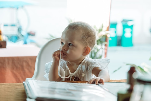 Foto niños leyendo el menú en el restaurante la niña está sentada en una silla alta para bebés en la cafetería de la calle