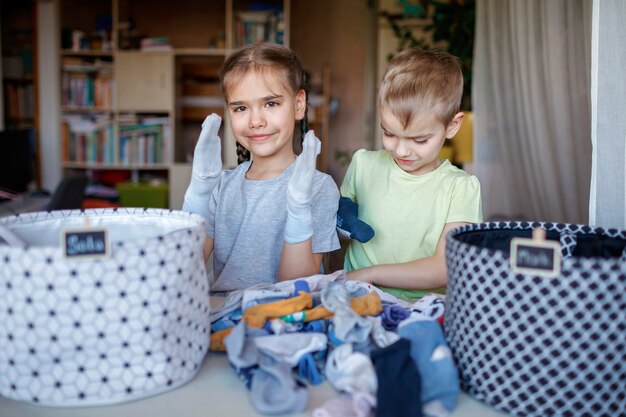 Foto los niños limpian la habitación, clasifican los calcetines y los colocan en cestas personales. rutina diaria con diversión