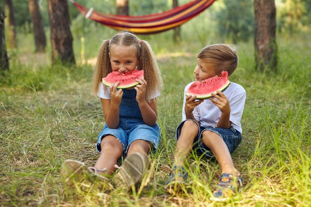 Niños lindos comiendo sandía en el jardín.