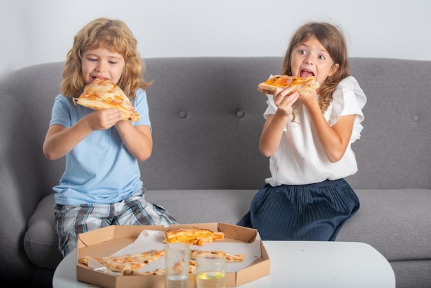 Niños lindos divertidos niña y niño comiendo pizza sabrosa Niños hambrientos comiendo pizza