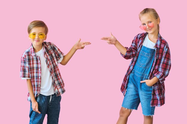 Foto niños lindos y elegantes con gafas de sol de color mirando a la cámara.