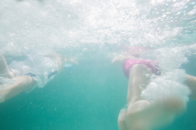 Niños lindos nadando bajo el agua en la piscina