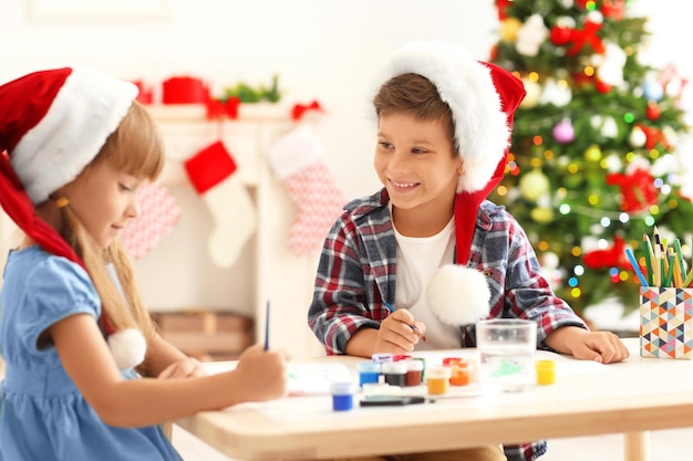 Niños lindos pintando cuadros para Navidad en la mesa