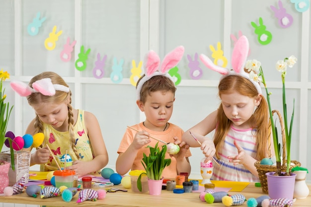 Niños lindos pintando huevos de Pascua en casa