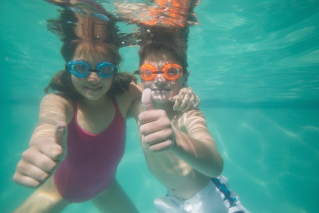 Niños lindos posando bajo el agua en la piscina en el centro de ocio