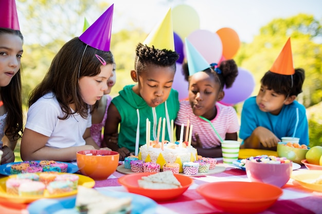 Niños lindos que soplan juntos en la vela durante una fiesta de cumpleaños