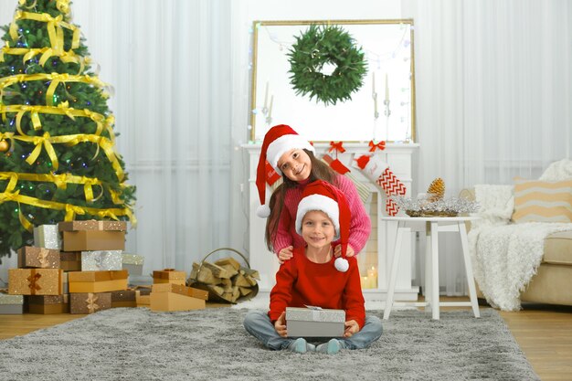 Niños lindos con regalo de Navidad en la sala de estar