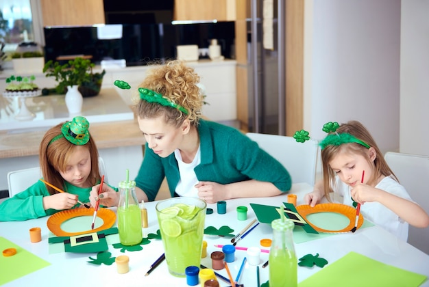 Niños con madre haciendo decoraciones.