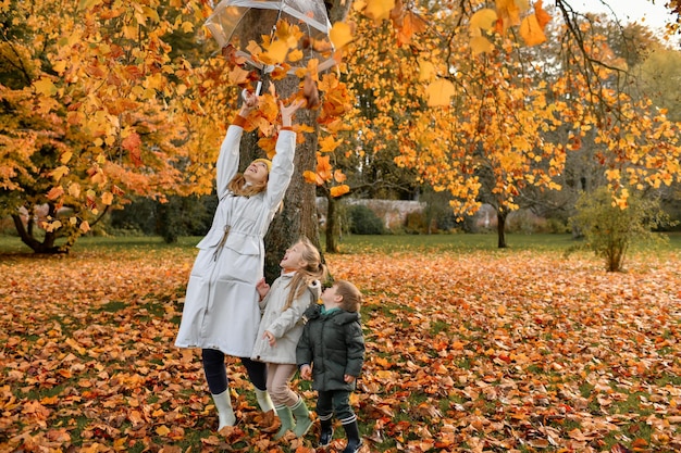 Los niños y la madre juegan en el parque de otoño.