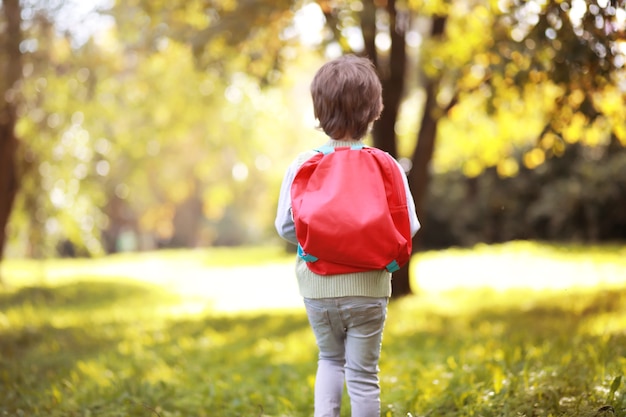 Niños con maletines para pasear por el parque. Vacaciones escolares. El inicio de los estudios infantiles.