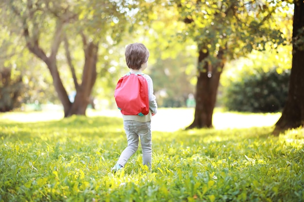 Niños con maletines para pasear por el parque. Vacaciones escolares. El inicio de los estudios infantiles.