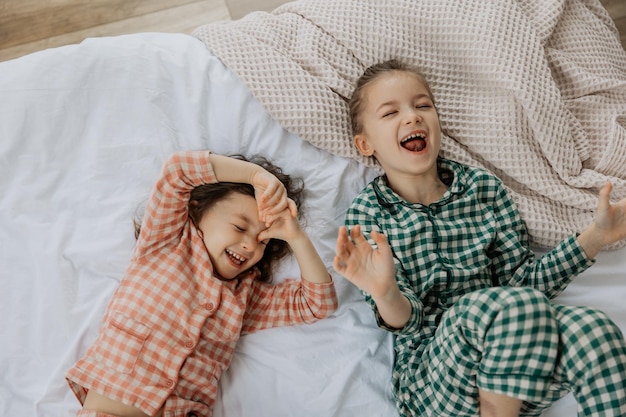 Foto niños de la mañana vista superior hermanas felices están acostadas en una cama niñas pequeñas de la mañana despertando en una cama