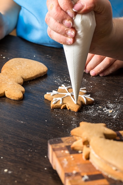 Niños a mano decorando galletas con azúcar.