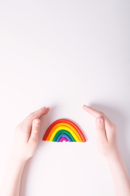 Niños manos alrededor de plastilina arco iris concepto de familia lgbt vista superior colores de la bandera gay fondo claro espacio de copia en la parte superior