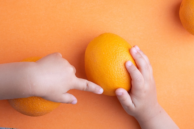 niños manos sosteniendo naranja