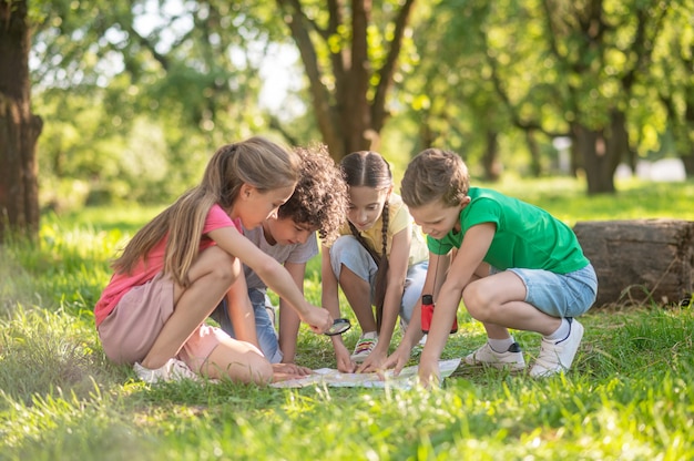 Niños con mapa y lupa sobre césped