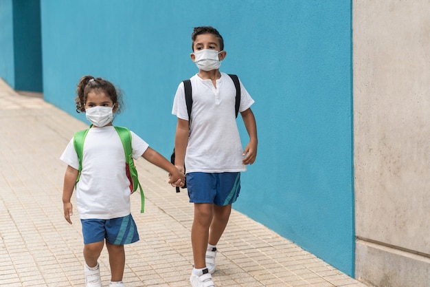 Foto niños con mascarilla que regresan a la escuela durante el brote de coronavirus: enfoque en la cara del niño