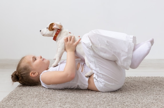 Los niños mascotas y concepto animal niña niño juega con su cachorro jack russell terrier en interiores