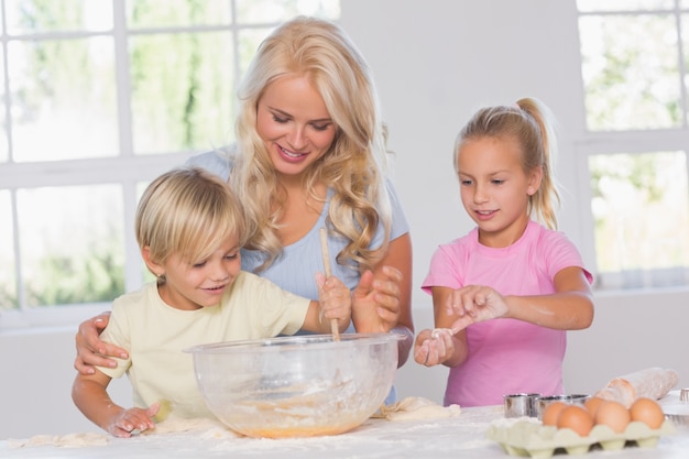 Niños mezclando masa con su madre