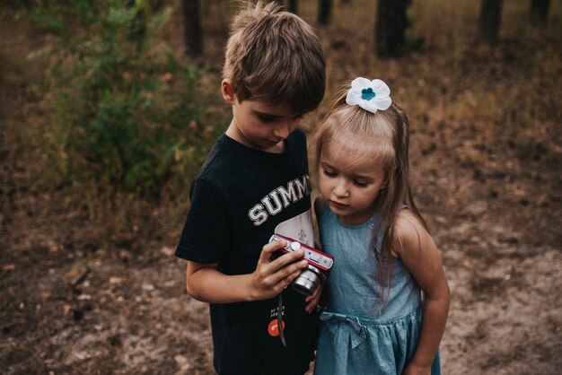 Los niños miran la foto de la cámara en el bosque.