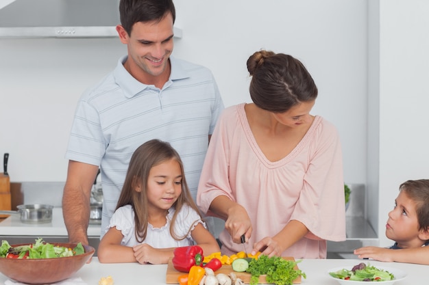 Niños mirando a su madre preparando verduras