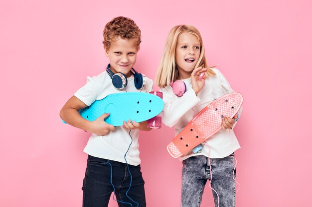 Foto niños montando patineta con auriculares patinetas en las manos fondo aislado