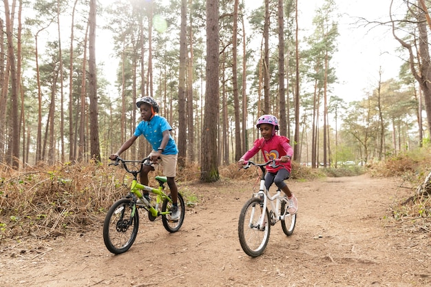 Foto niños montando su bicicleta en el bosque.