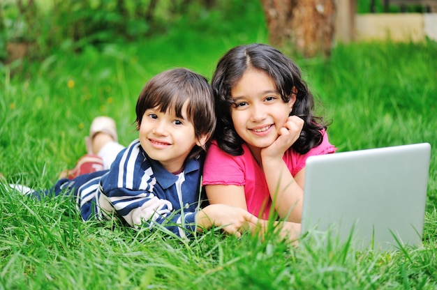 Niños en la naturaleza con la computadora portátil