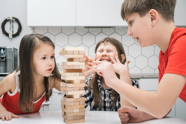 Niños nerviosos preocupados y apasionados jugando al equilibrio del tablero juego de torre de ladrillos de madera Niño tratando de mover el cubo de madera fuera de la línea