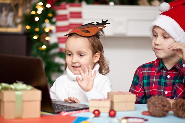 niños niña y niño con gorro de Papá Noel usando una tableta digital portátil.