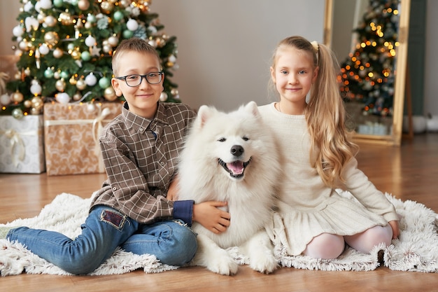 Niños niña y niño con perro samoyedo en escena navideña