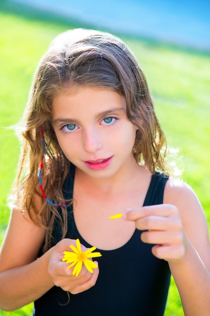 Foto niños niña probando el amor con pétalos de flores amarillas margarita