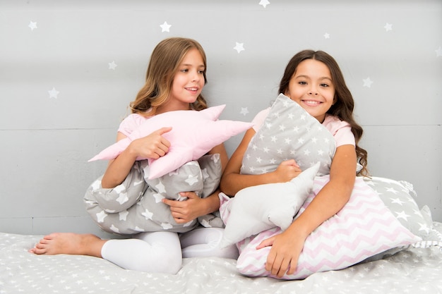 Los niños de las niñas abrazan la almohada linda. lindas almohadas