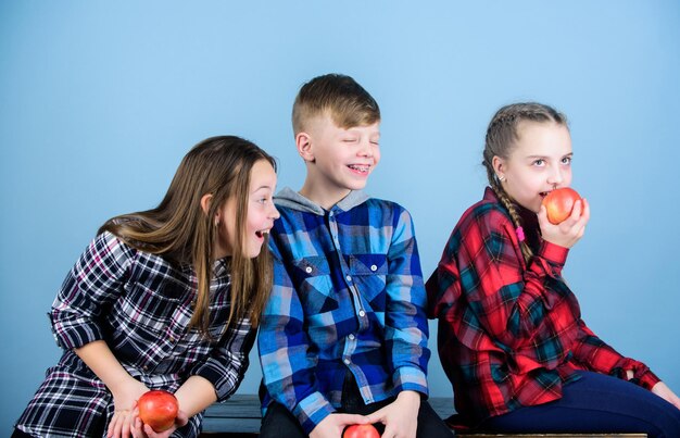 Niños y niñas amigos comen bocadillos de manzana mientras se relajan Dieta saludable y nutrición vitamínica Concepto de bocadillos escolares Grupo de adolescentes alegres que se comunican y comen manzanas Adolescentes con bocadillos saludables