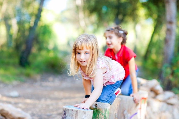 Niños niñas jugando en troncos en la naturaleza del bosque