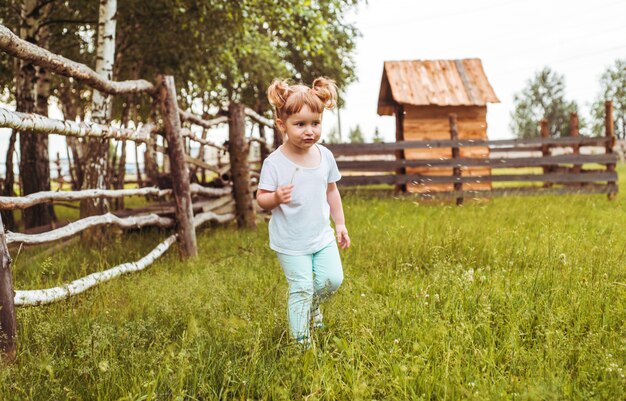 Niños, niñas de pie junto a una valla en el pueblo. paseos por el campo. agricultura. ecología e infancia feliz, hermosa niña.