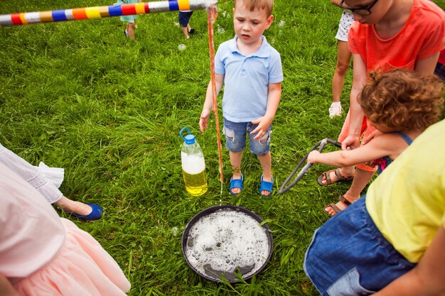 Los niños y las niñas se preparan con entusiasmo para crear pompas de jabón Los niños usan agua jabonosa y herramientas especiales