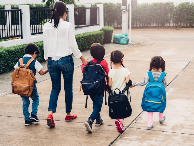 Niños niño hijo niña y niño jardín de infantes caminando yendo a la escuela tomados de la mano con madre mamá