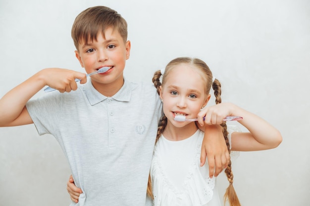 Los niños, un niño y una niña, se cepillan los dientes y se ríen aislados en un fondo blanco odontología pediátrica higiene y limpieza de dientes