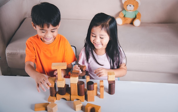 Niños niño y niña jugando con constructor edificio de bloques de madera