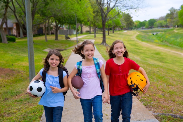 Niños niños niñas caminando a la escuela con pelotas deportivas