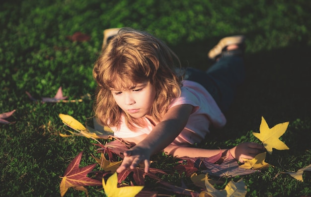 Los niños de otoño caen hojas al aire libre